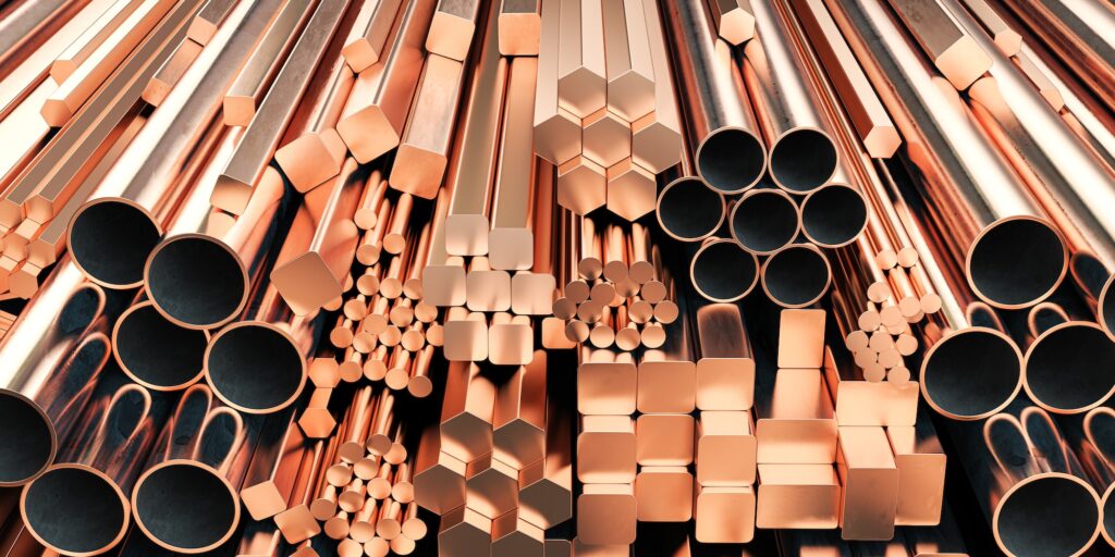 Copper tubes and different profiles in warehouse background. Different copper metal rolled products.